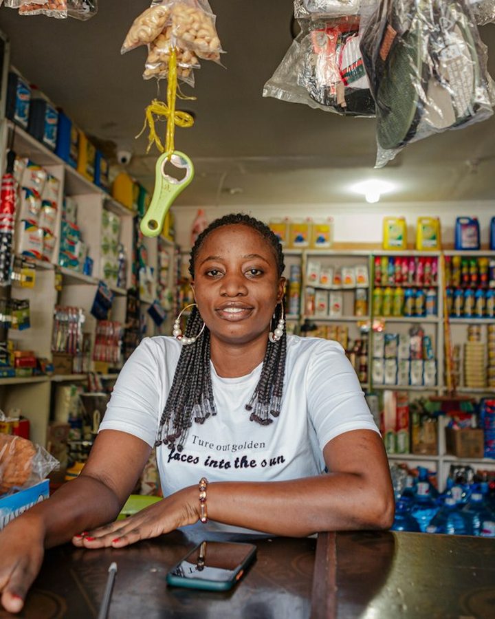 A shopkeeper at her counter, surrounded by shelves of goods